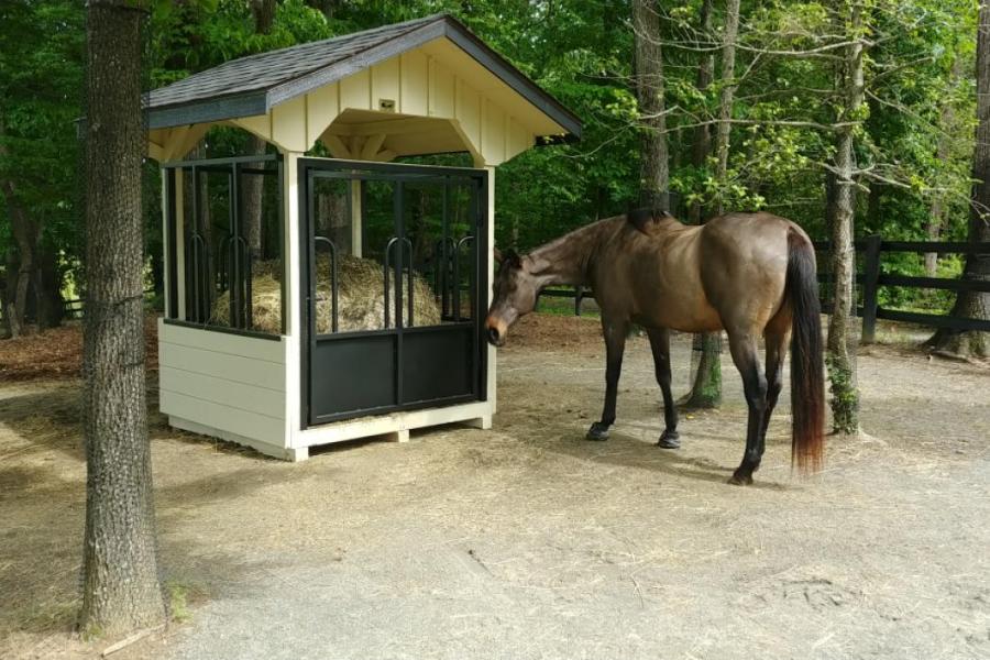 A covered hay bale feeder for horses