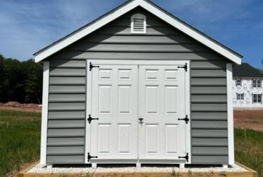 Grey-blue victorian style shed. Photo taken of the side entry's double doors.