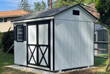 side view of shed with double doors, white siding  and black trim
