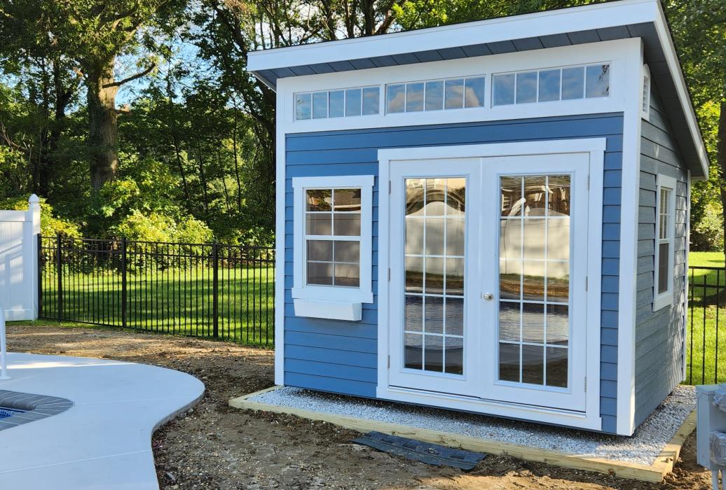 Backyard Studio Shed in Light Blue next to pool.