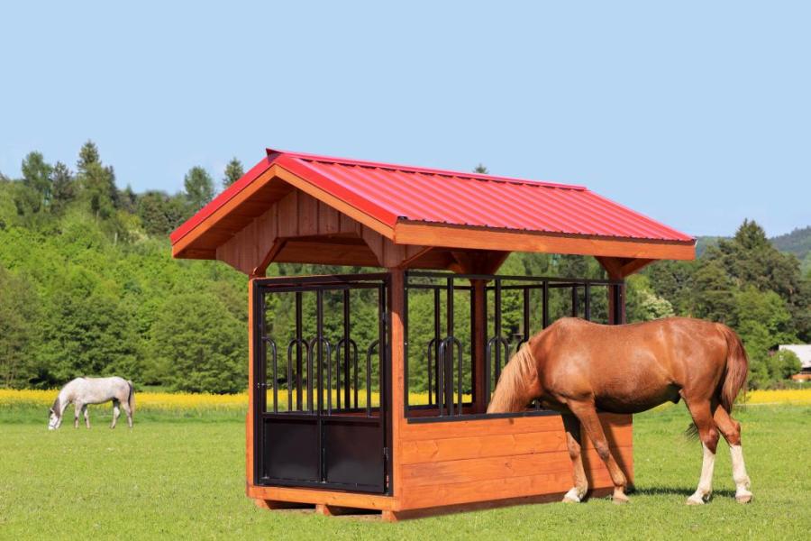 Horse eating from a round hay bale feeder with a roof